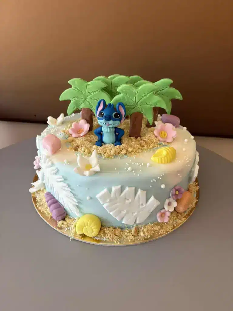 Stitch figurás torta pálmafákkal és virágdíszekkel.